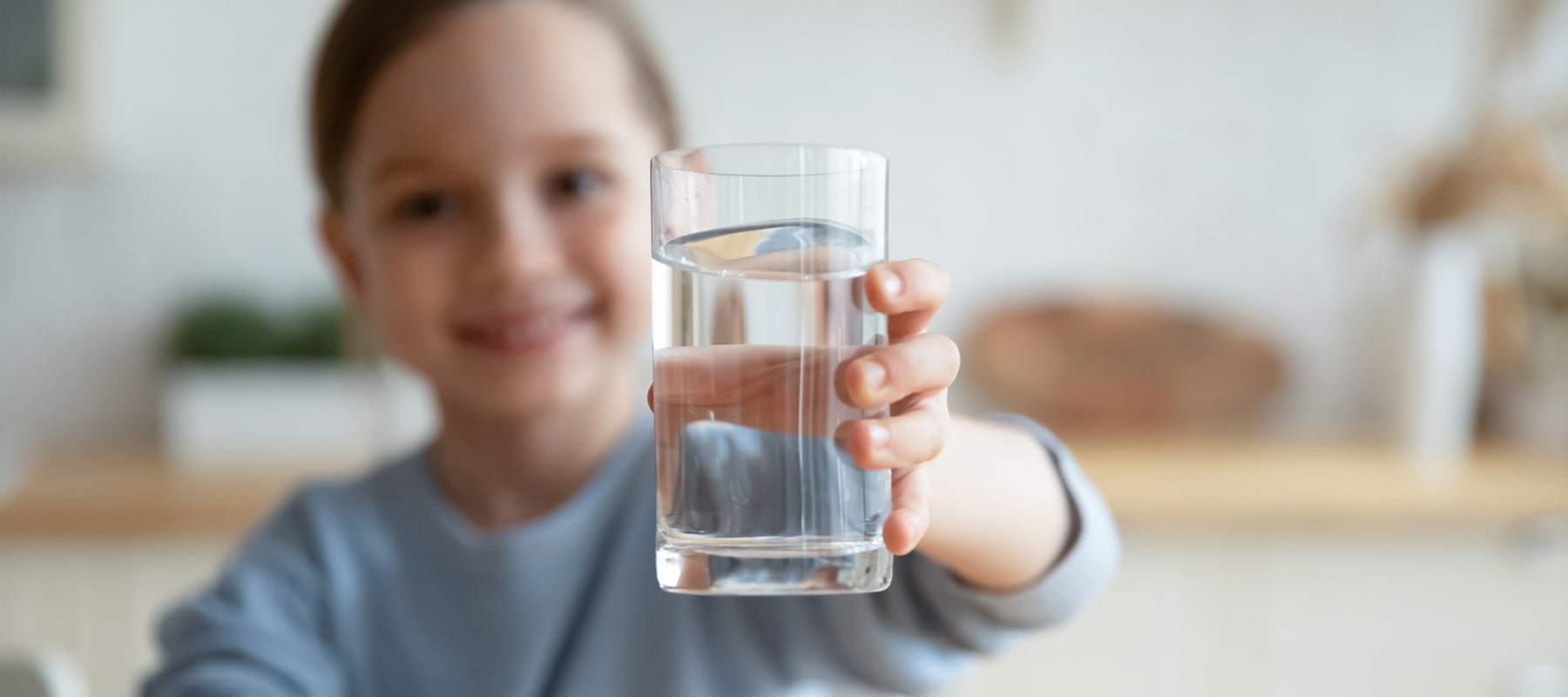 A glass of vapor distilled water in the hand of a smiling child