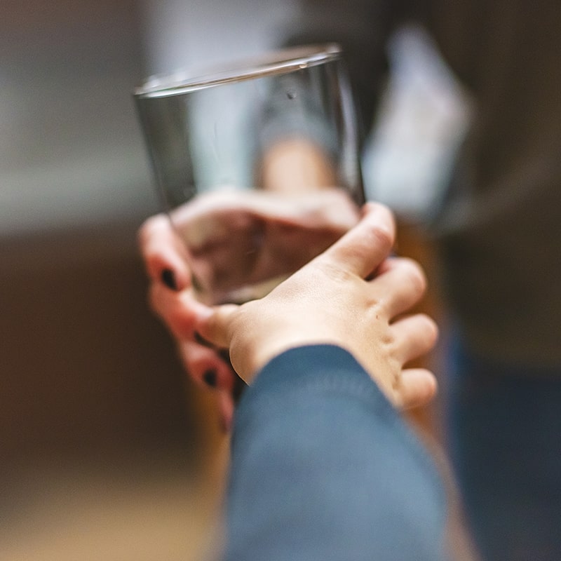 a glass of alkaline water being handed to a child