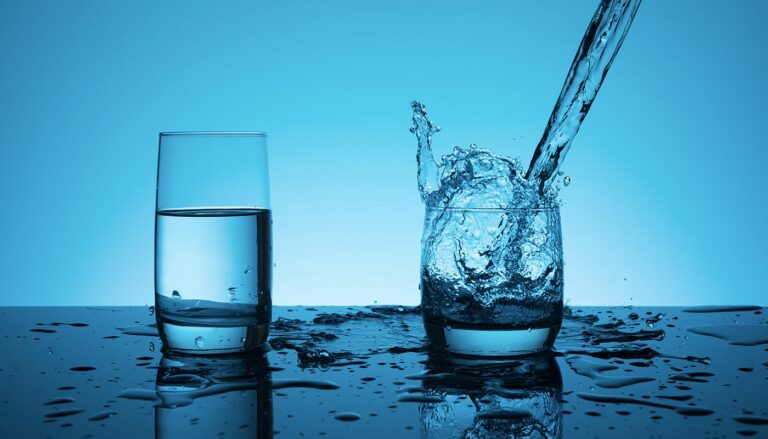 Purified water being poured into a glass with another glass filled with purified water kept beside it.