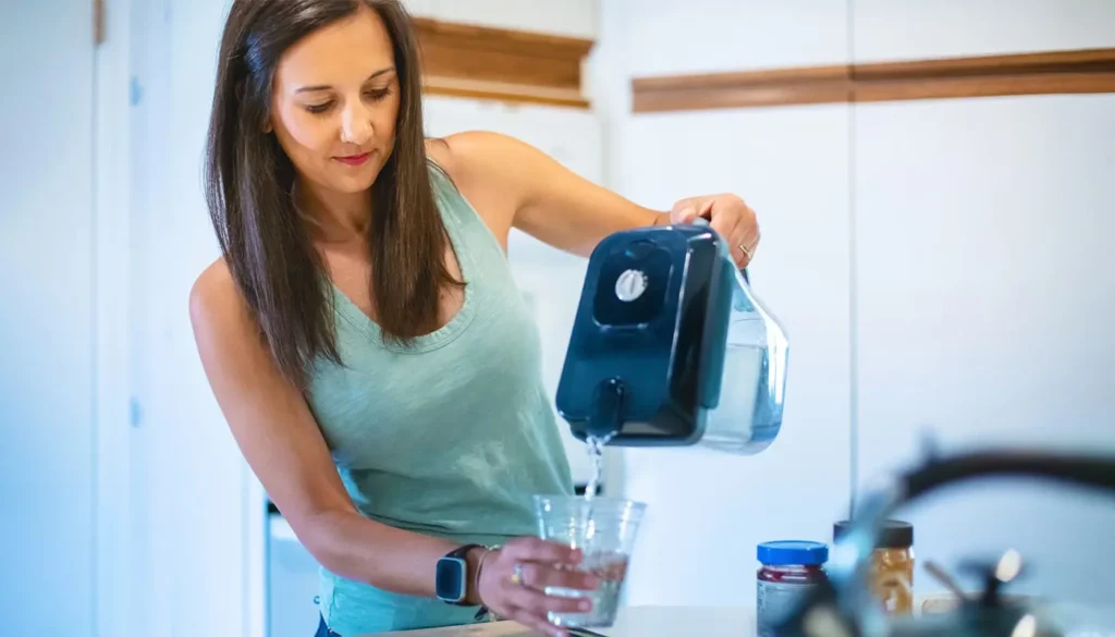 A woman pouring filtered water in a glass.
