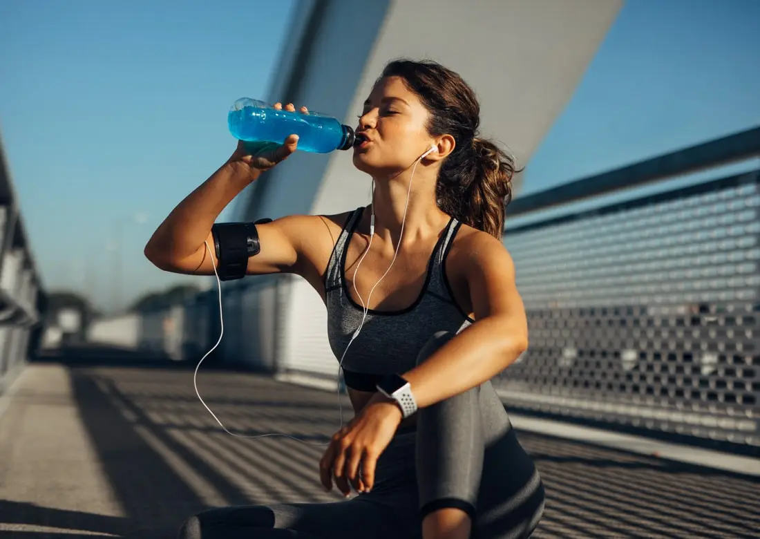A women drinking distilled water while taking rest from jogging