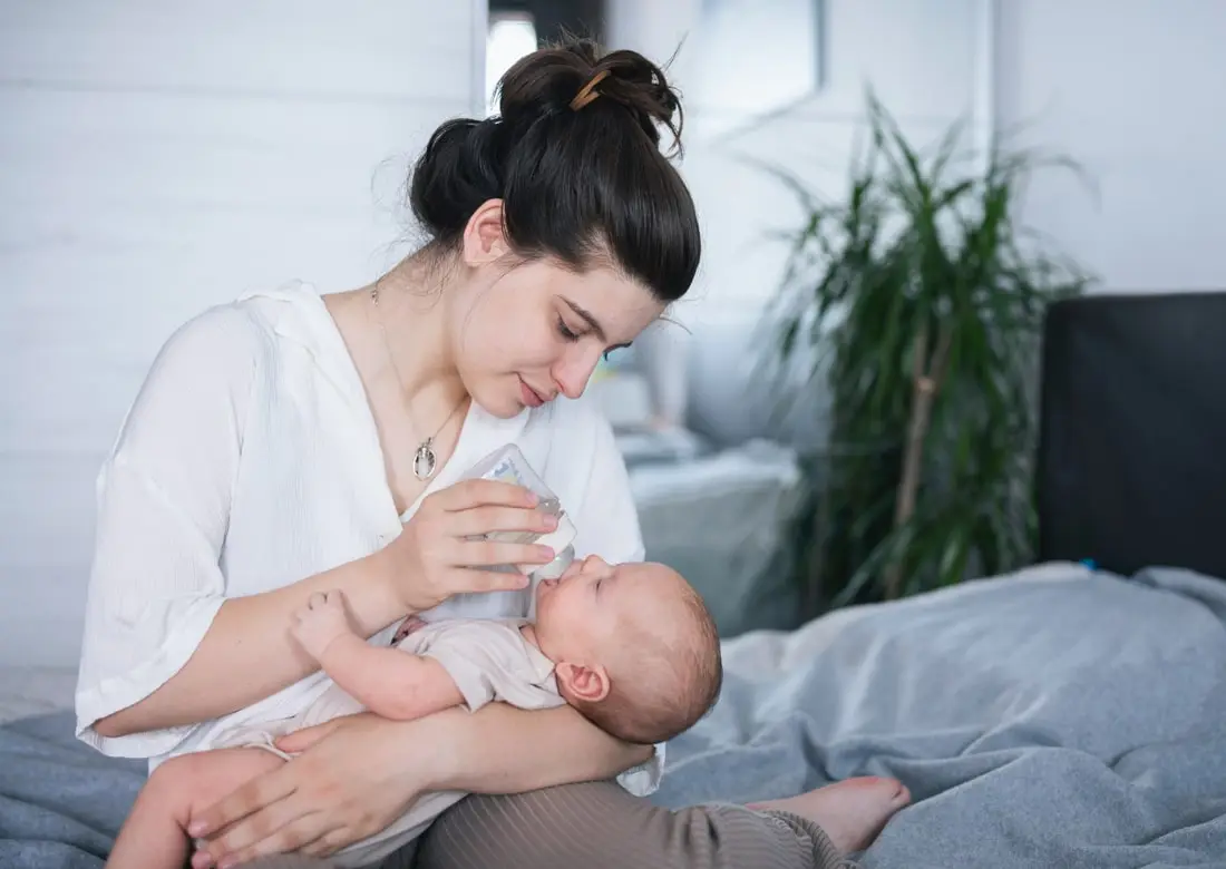 mother giving formula made with nursery water to her baby