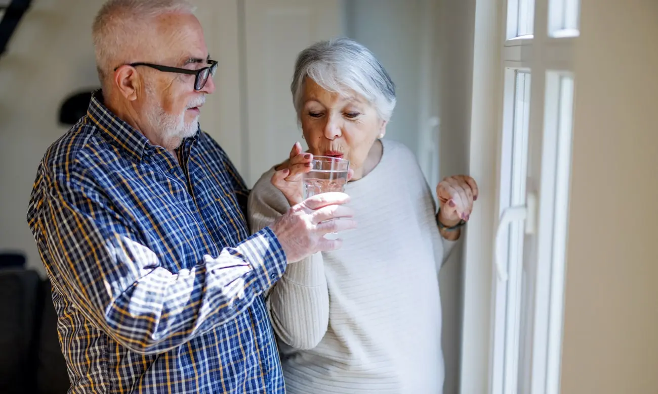 Elder husband giving Premium distilled water to his wife in a glass